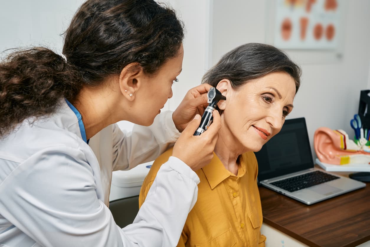 Senior woman receiving an ear exam stock photo