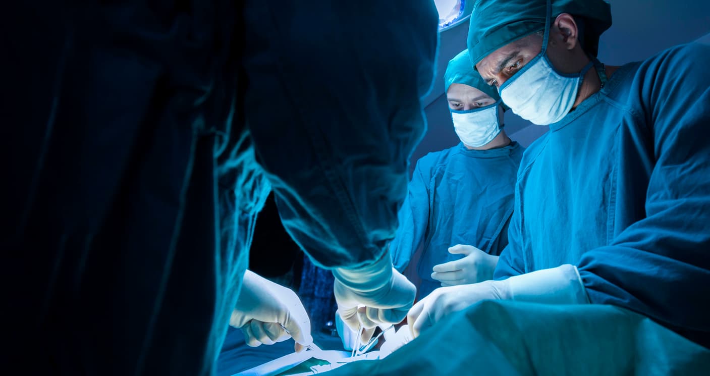 plastic surgeons standing over a patient stock image